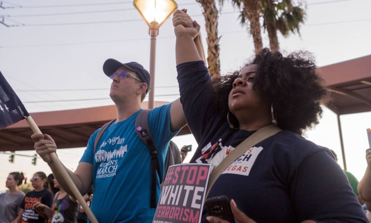 James Dunbar, à esquerda, e Deborah Harris dão as mãos durante vigília para as vítimas em Charlottesville, no domingo, no Memorial de Martin Luther King Jr. em Las Vegas. Manifestantes protestando contra o ódio e o racismo se reuniram em todo o país no domingo Foto: Elizabeth Brumley / AP
