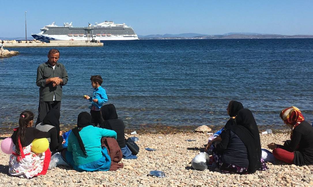 
Refugiados se reúnem na praia de Chios, enquanto um navio de cruzeiro chega com turistas: : fim do verão coincide com o aumento de chegada de imigrantes, que aproveitam o relaxamento na patrulha na costa turca
Foto:
Lucila Runnacles
