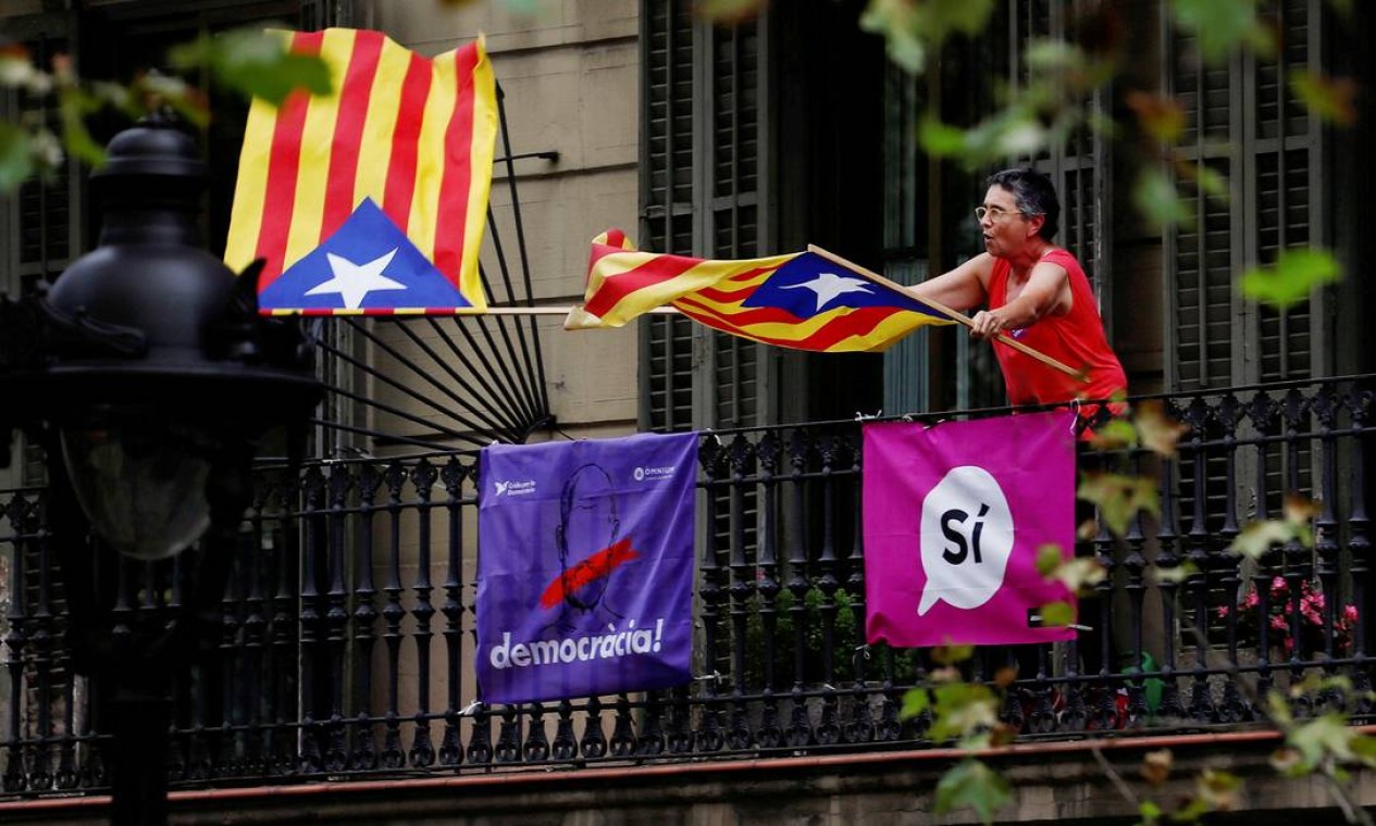 Mulher sacode bandeiras em sinal de apoio à separação catalã; identidade secular e crise econômica aumentam sentimento nacionalista Foto: JUAN MEDINA / REUTERS