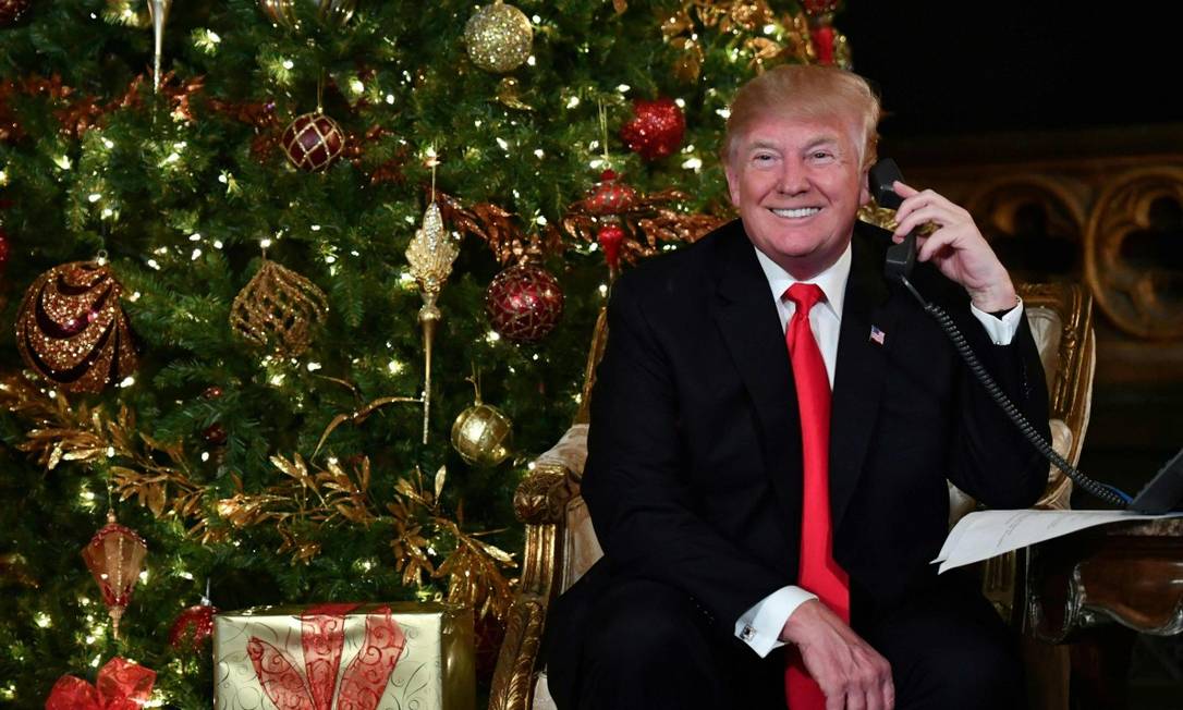 Donald Trump fala ao telefone na sua primeira véspera de natal como presidente dos EUA Foto: NICHOLAS KAMM / AFP