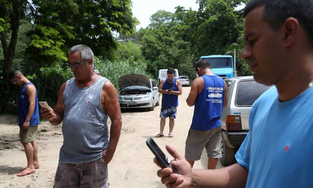 
O distrito de Cabuçu, em Itaboraí, é um dos 2.000 distritos do país que não contam cobertura de celular. Valdir Batista (mais velho) e Danilo Santos (direita) tentam conseguir sinal
Foto:
/
Custódio Coimbra
