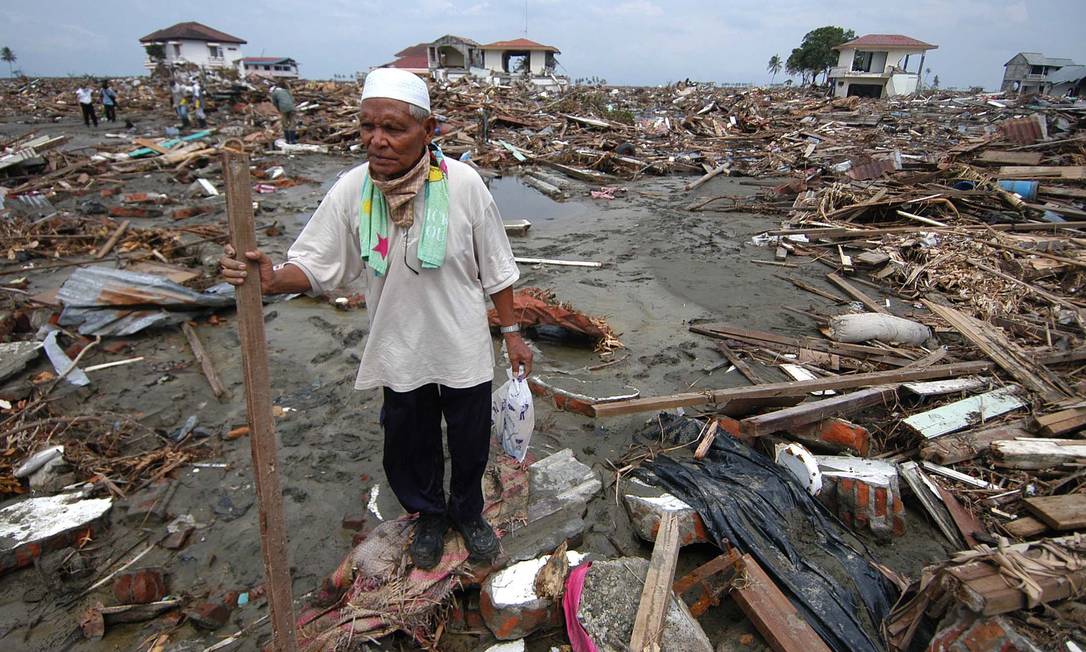 Homem caminha em meio a destroços de tsunami na Indonésia, em 2005 Foto: Yusuf Ahmad / Reuters