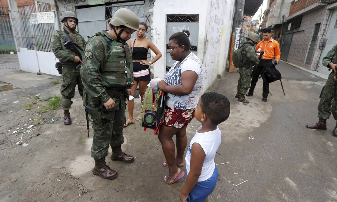Uma militar revista mochila de menino durante operação na Favela Kelson's Foto: Domingos Peixoto / Agência O Globo