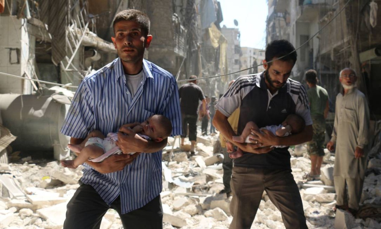 Em setembro de 2016, sírios carregam bebês em meio a bombardeios contra Aleppo: ofensiva sangrenta do regime reconquistou maior bastião rebelde da guerra, ao custo de dezenas de milhares de civis mortos Foto: AMEER ALHALBI / AFP