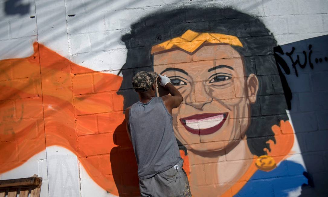 Homem grafita mural com o rosto da vereadora Marielle durante protesto na Maré Foto: Mauro Pimentel / AFP