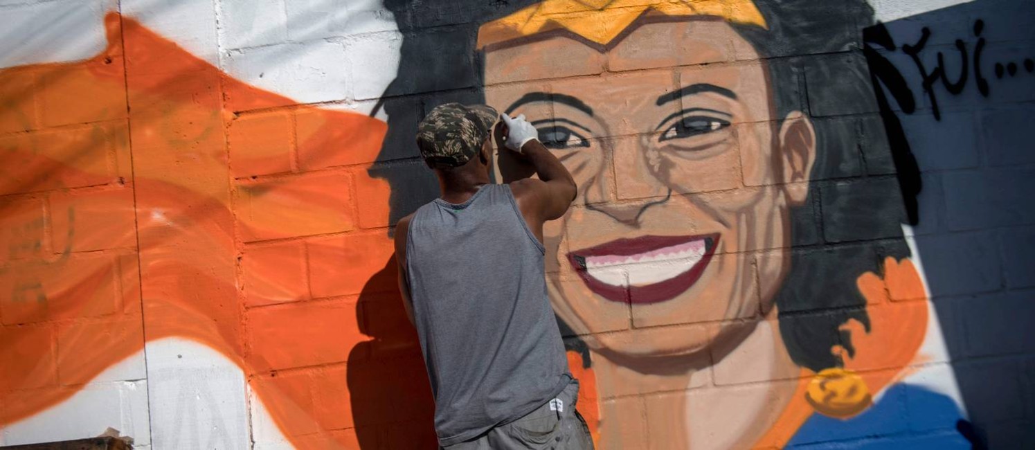 Homem grafita mural com o rosto da vereadora Marielle durante protesto na Maré Foto: Mauro Pimentel / AFP