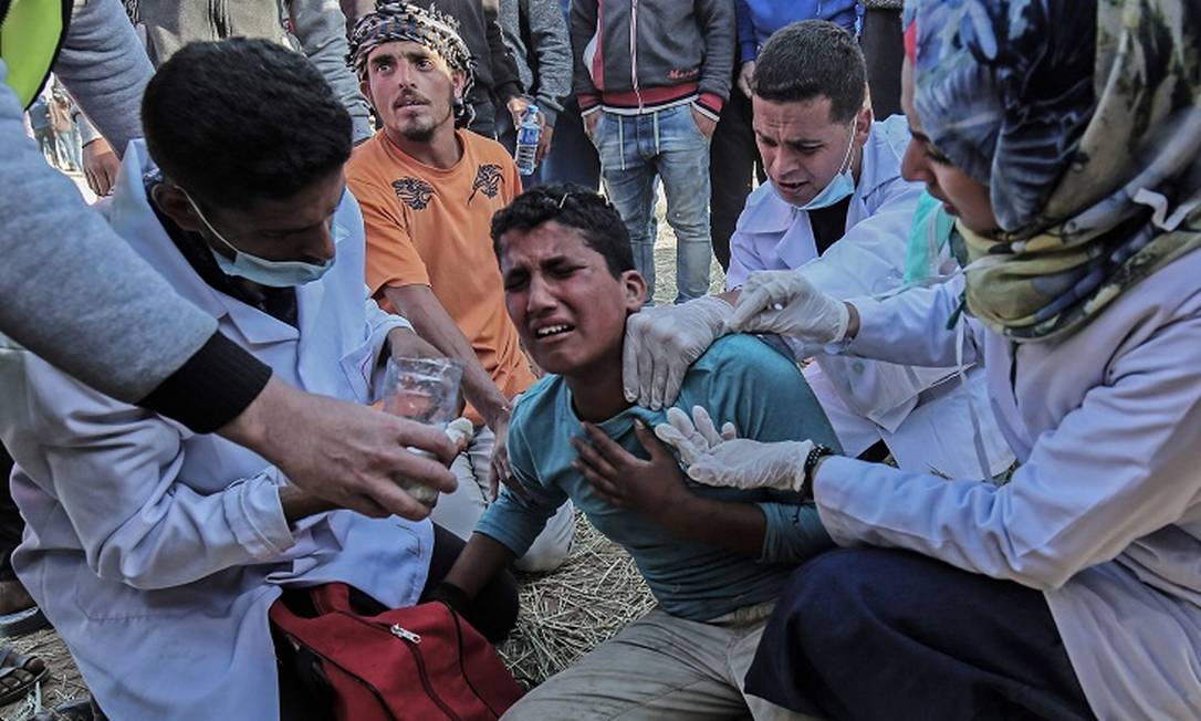 Manifestantes palestinos foram feridos durante protesto na sexta-feira. Dezesseis foram mortos. Na imagem, equipe médica presta atendimento Foto: SAID KHATIB / AFP