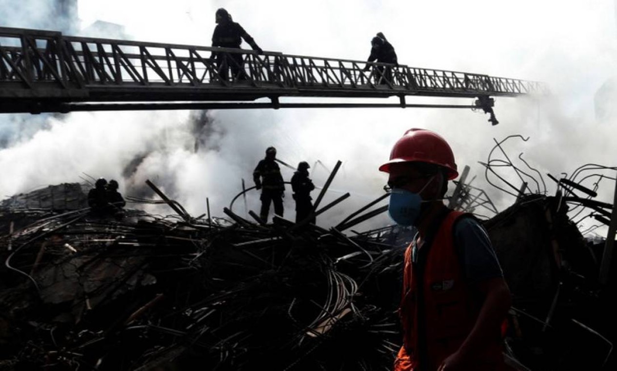 Após o desmoronamento do prédio, bombeiros tentavam extinguir as últimas chamas Foto: Leonardo Benassatto / Reuters