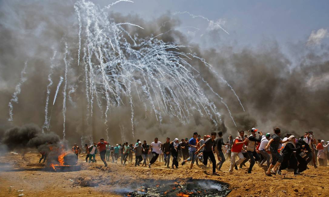 Palestinos fogem do gás lacrimogêneo perto da fronteira entre a Faixa de Gaza e Israel Foto: MOHAMMED ABED / AFP