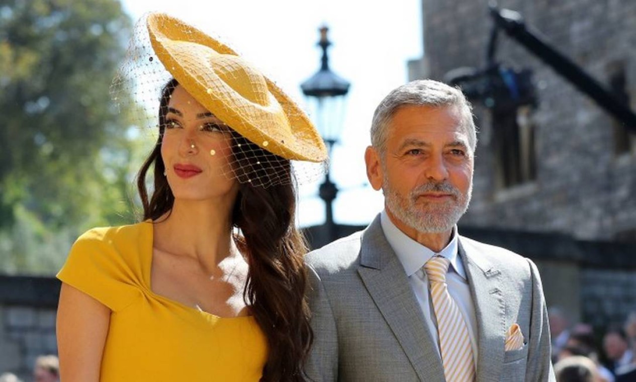Diz o protocolo real: mulheres devem usar chapéus em eventos como o casamento de um membro da realeza. Na imagem, Amal e George Clooney Foto: GARETH FULLER / AFP