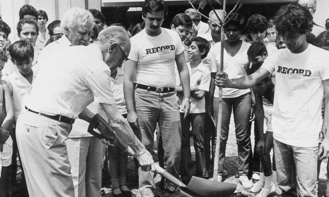 Drummond (de pá na mão) planta uma muda ao lado de Jorge Amado, no pátio da Record, em 1984 Foto: Divulgação