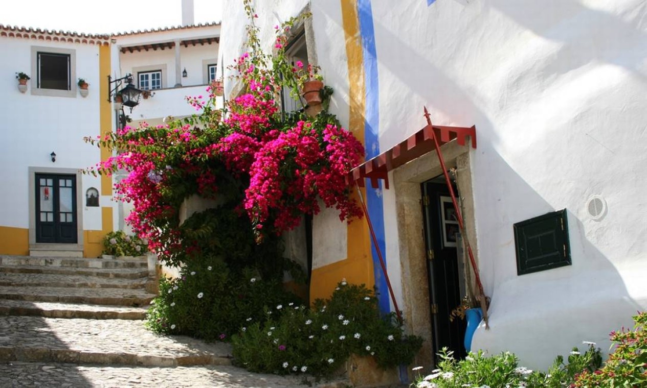 Ruas charmosas e floridas fazem parte do encanto da vila medieval de Óbidos Foto: Divulgação