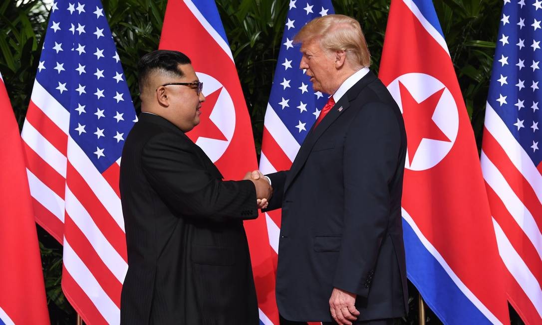 No primeiro encontro entre um presidente americano e um lÃ­der norte-coreano, Donald Trump aperta a mÃ£o de Kim Jong-un no luxuoso Hotel Capella, em Cingapura. Na agenda, a desnuclearizaÃ§Ã£o da Coreia do Norte SAUL LOEB / AFP