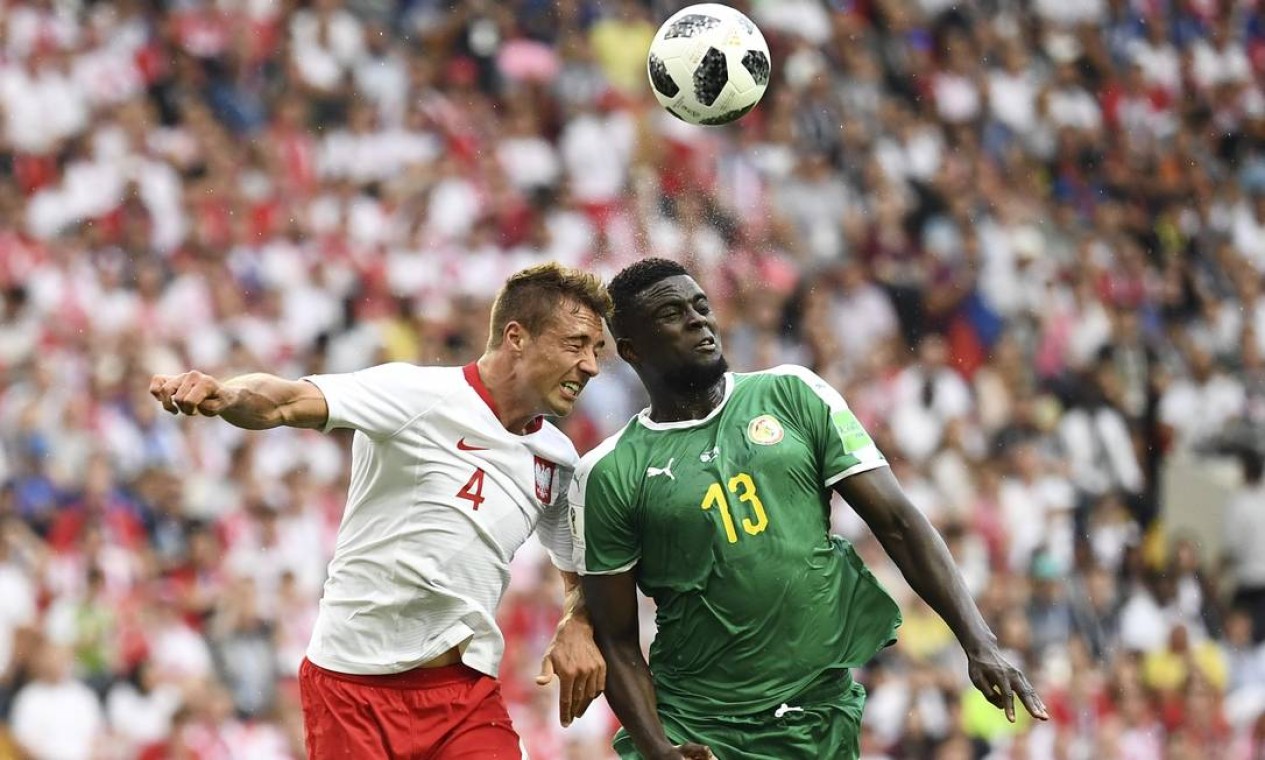 O brasileiro naturalizado polonês, Thiago Cionek (esquerda) e o meia Alfred N'Diaye de Senegal disputam bola pelo alto. O brasileiro marcou contra o primeiro gol da partida, abrindo o placar para os africanos Foto: FRANCK FIFE / AFP