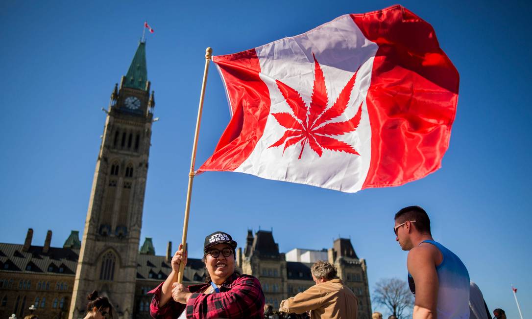 Mulher segura uma bandeira canadense onde se vê uma folha de maconha, em frente ao Parlamento, em Ottawa Foto: Chris Roussakis / AFP