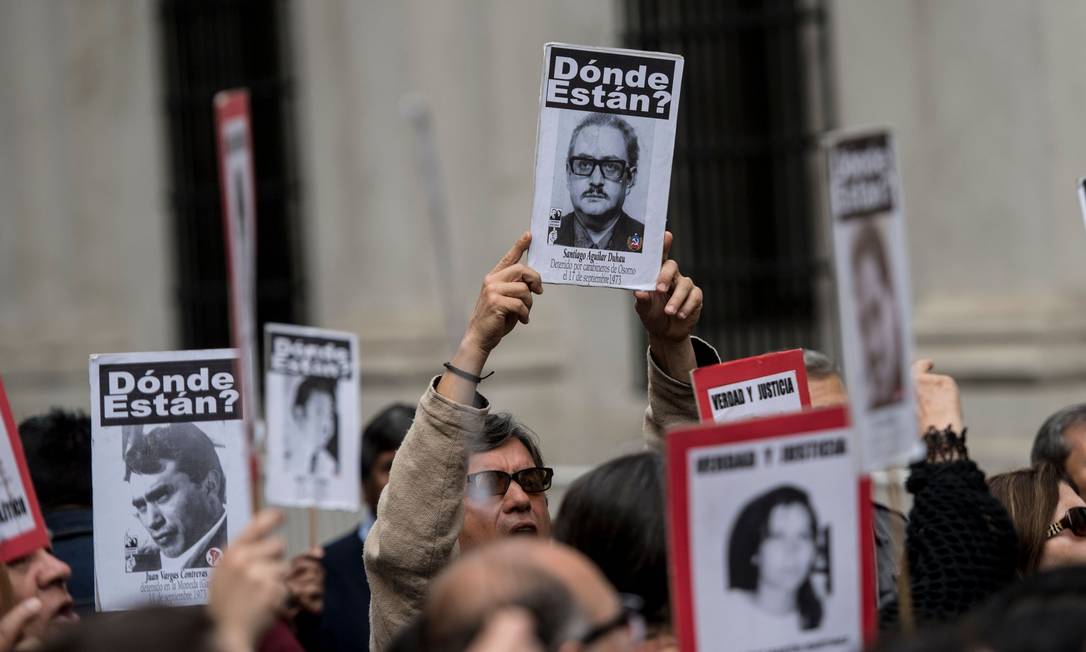 Ativistas levantam cartazes com fotos de pessoas que desapareceram durante a última ditadura no Chile Foto: MARTIN BERNETTI / AFP