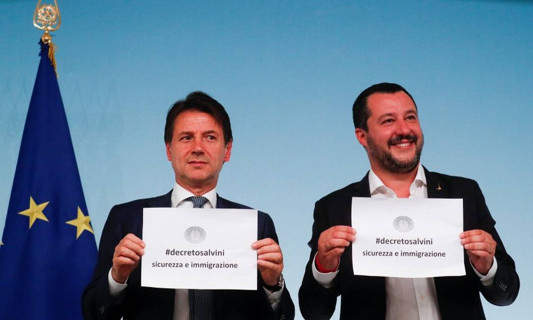 Primeiro-ministro italiano, Giuseppe Conte, e ministro do Interior, Matteo Salvini, levantam papeis em que se lê "#decretosalvini, segurança e imigração" após aprovação pelo Parlamento de proposta de lei Foto: ALESSANDRO BIANCHI / REUTERS