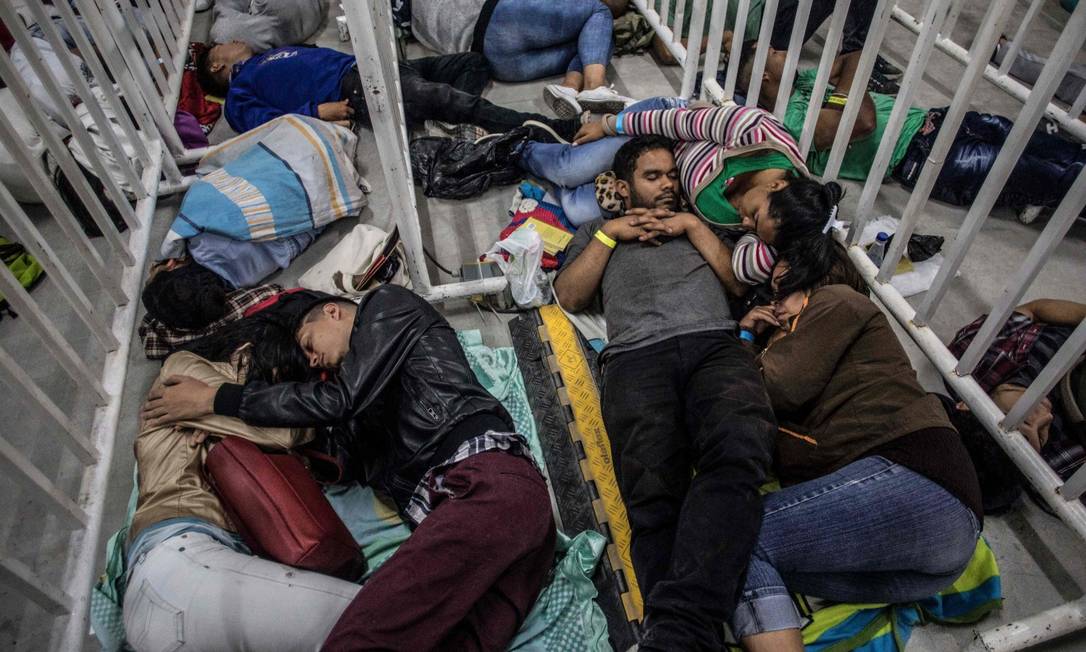 Imigrantes venezuelanos dormem na fila para comparecer a feira de empregos em Medellín, na Colômbia Foto: JOAQUIN SARMIENTO / AFP