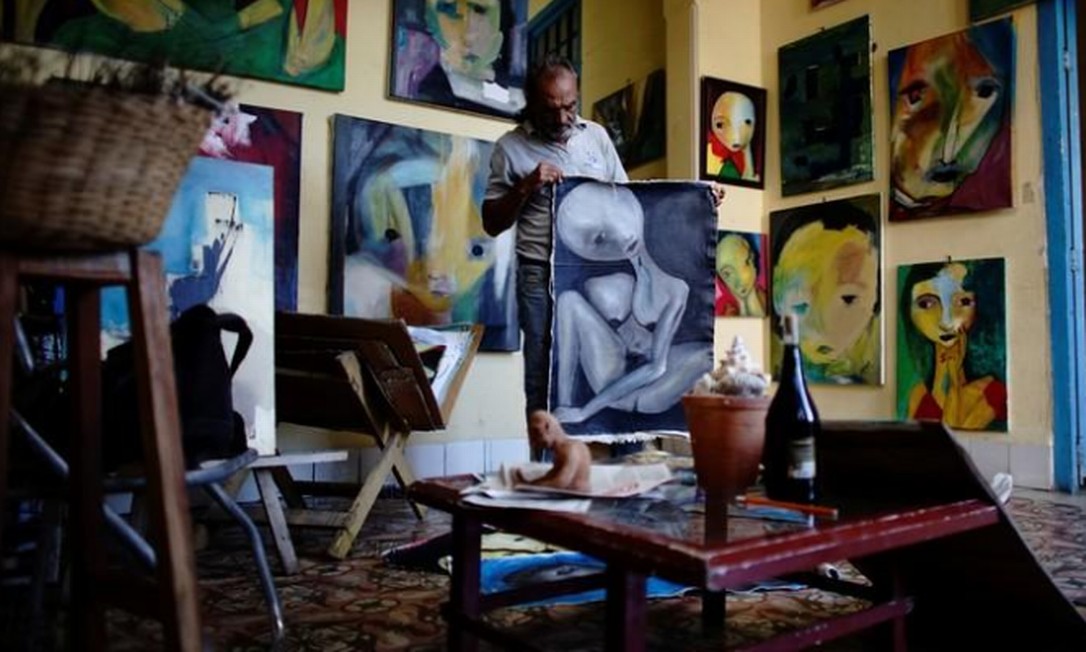 O pintor Roberto Loeje em meio a suas obras em seu ateliê em Havana Foto: Alexandre Meneghini / Reuters