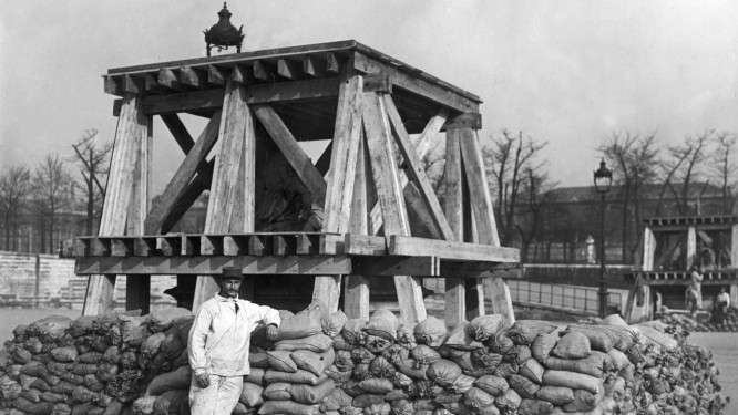 Homem posa em frente a uma estÃ¡tua superprotegida no Jardim de Tuileries (o primeiro jardim pÃºblico de Paris), durante a Primeira Guerra Mundial. Os monumentos foram cercados por sacos de areia para tentar evitar danos em caso de ataque alemÃ£o Foto: Hulton Archive / Getty Images