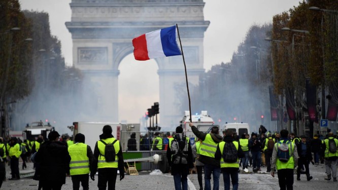  Manifestantes do movimento dos coletes amarelos carregam uma bandeira da França durante protesto na avenida dos Champs-Elysees, em Paris Foto: BERTRAND GUAY / AFP