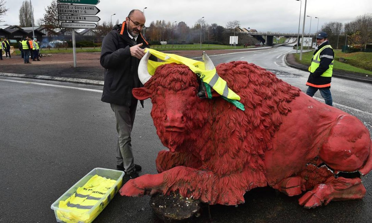 Um manifestante coloca um colete amarelo numa estátua de um bisão (em referência ao emblema "smart bison", de segurança rodoviária), na estrada em Saint Saturnin, perto de Le Mans, noroeste da França Foto: JEAN-FRANCOIS MONIER / AFP