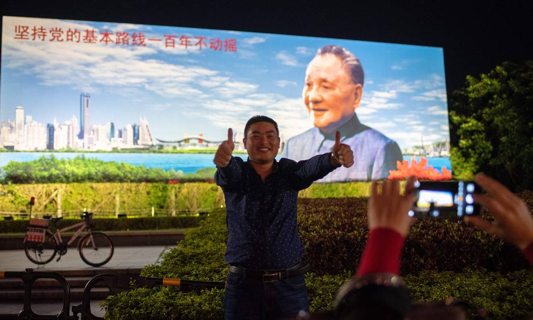 Homem posa em frente a outdoor mostrando Deng Xiaoping, que iniciou as reformas econômicas no país há 40 anos Foto: NICOLAS ASFOURI / AFP