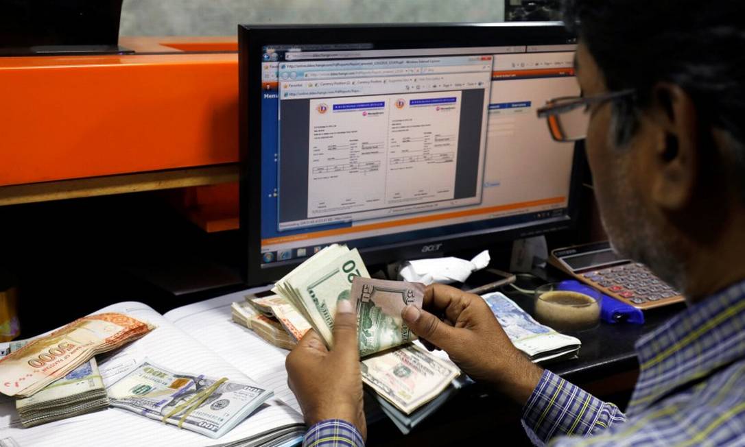 Homem conta cédulas de dólar, a moeda oficial dos Estados Unidos Foto: Akhtar Soomro / Reuters