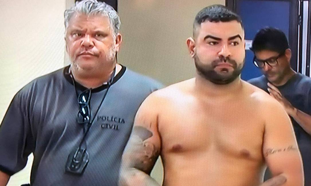 Policial conduz Renatinho Problema (sem camisa), preso em Guapimirim Foto: Reprodução / TV Globo