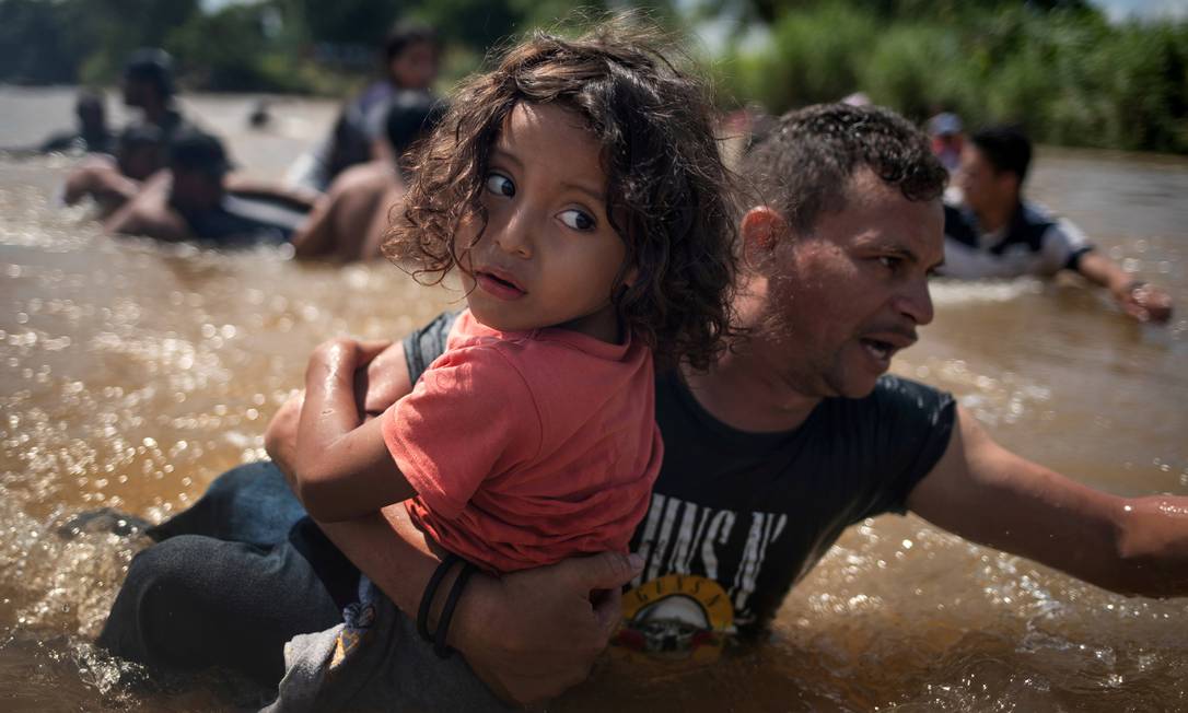 Pai e filha atravessam rio durante viagem de Honduras até os Estados Unidos; eles participavam da caravana migrante centro-americana que partiu de San Pedro Sula em outubro passado Foto: ADREES LATIF / REUTERS