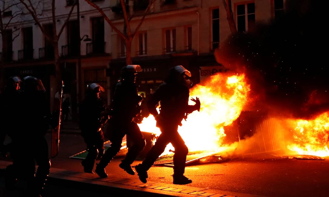 Policiais correm diante do fogo, em Paris Foto: GONZALO FUENTES / REUTERS