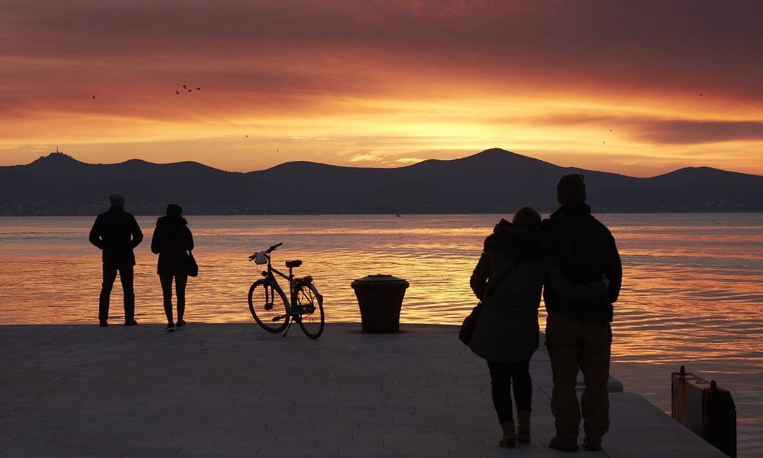 Pessoas apreciam o pôr do sol em Zadar, charmosa cidade litorânea na Croácia Andy Haslam / The New York Times