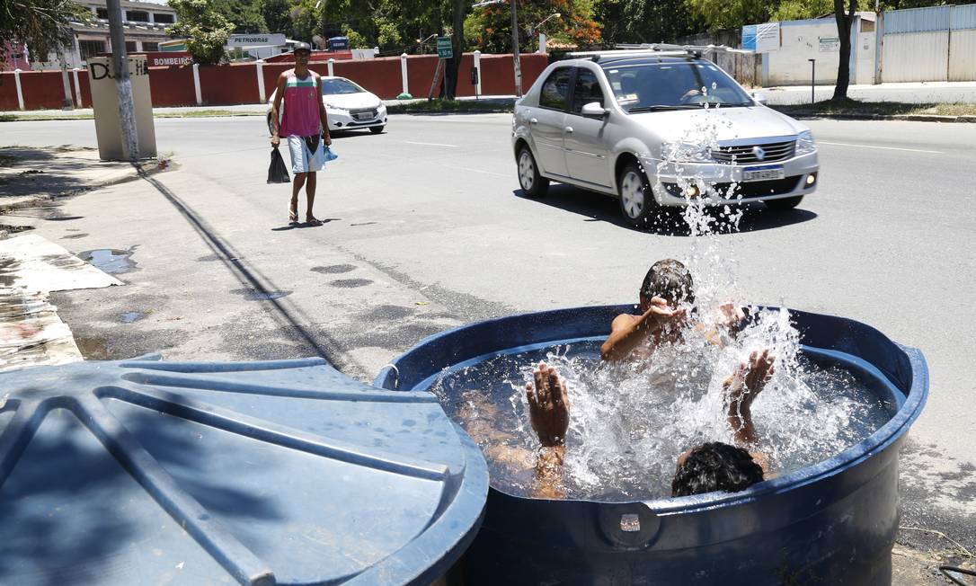 Garotos improvisam uma piscina em rua de São Cristóvão; recipientes que armazenam água se tornam focos potenciais de mosquitos Foto: Marcos Ramos / Agência O Globo