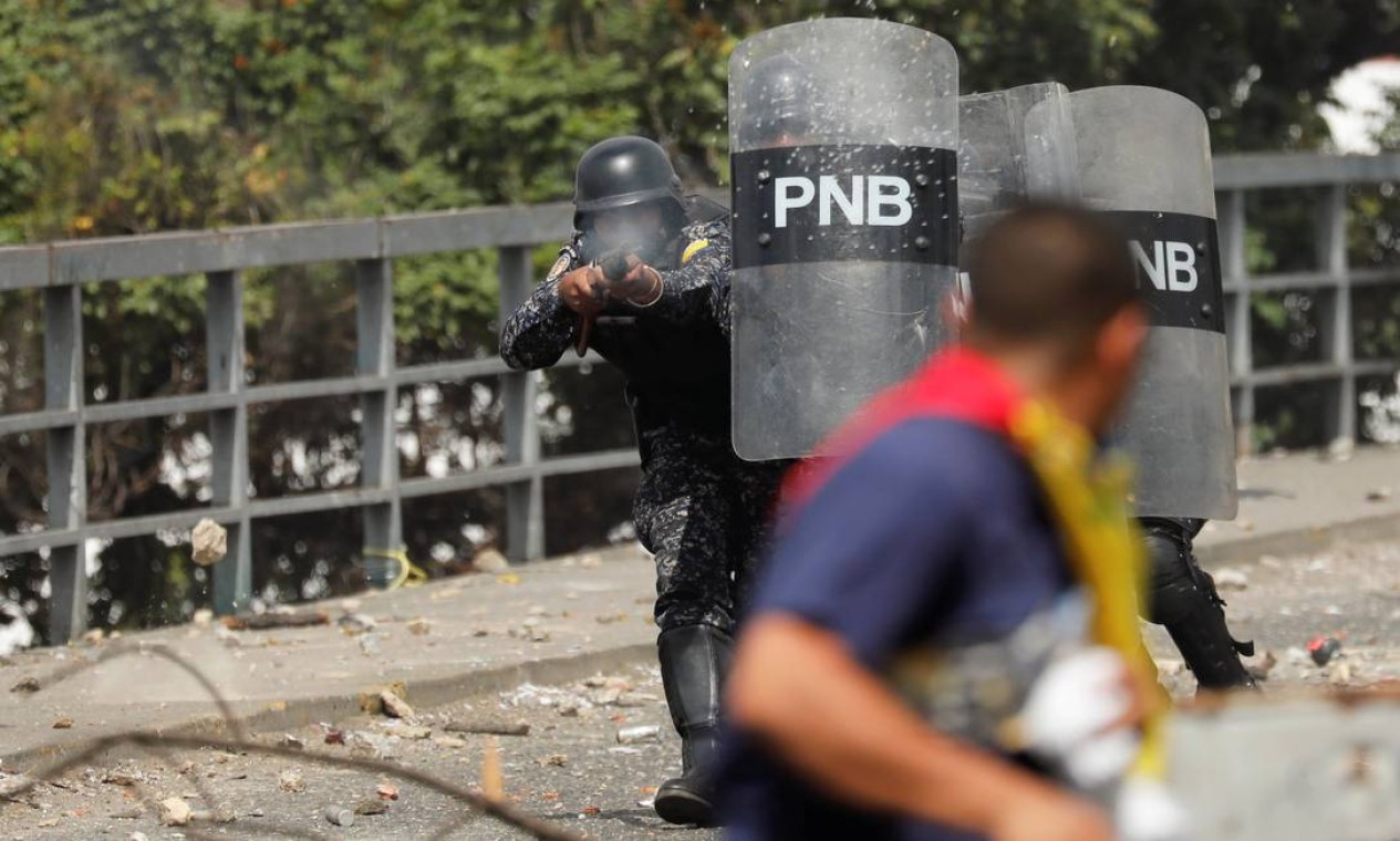 Agente de segurança dispara balas de borracha contra manifestantes em Caracas; repressão a marchas é frequente no país Foto: STRINGER / REUTERS