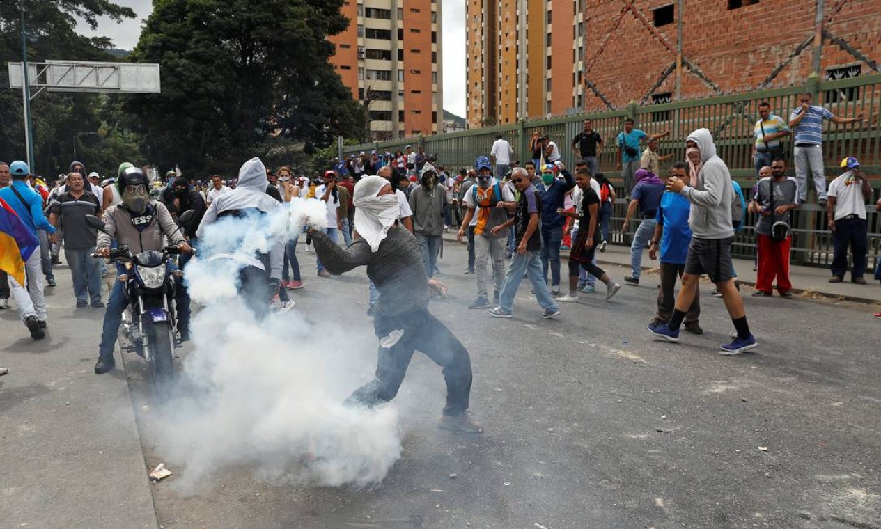 Manifestante joga de volta uma bomba de gás lacrimogêneo durante protesto Foto: STRINGER / REUTERS