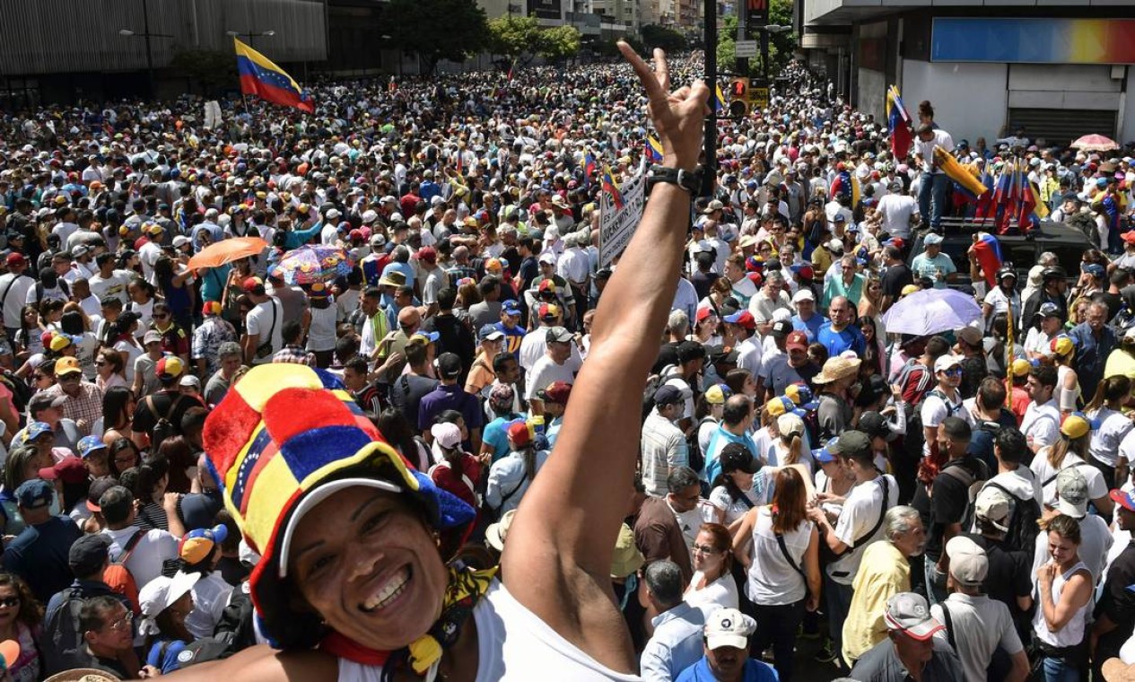 Manifestante de oposição sorri para câmeras no meio da multidão que saiu para protestar na Venezuela contra Maduro Foto: YURI CORTEZ / AFP