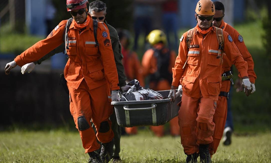 Bombeiros militares transportam o cadáver de uma vítima recuperada da lama DOUGLAS MAGNO / AFP