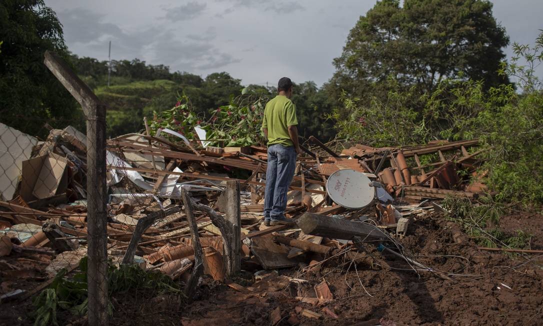 Moradores da comunidade Parque da Cachoeira olham os destroços de suas casas após o rompimento da barreira Mauro Pimentel / AFP