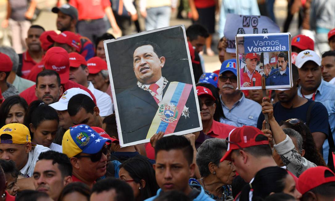 Funcionários da estatal PDVSA levam retrato de Chávez em manifestação convocada por Maduro; seu governo perdeu apoio de e-ministros do fundador da Revolução Bolivariana Foto: YURI CORTEZ / AFP/31-1-2019