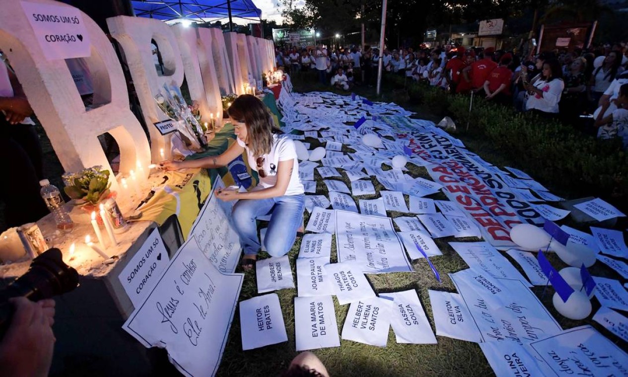 Um altar em homenagem às vítimas foi montado no letreiro com o nome de Brumadinho. Na foto, uma mulher acende uma vela durante um ato em memória das vítimas Foto: WASHINGTON ALVES / REUTERS