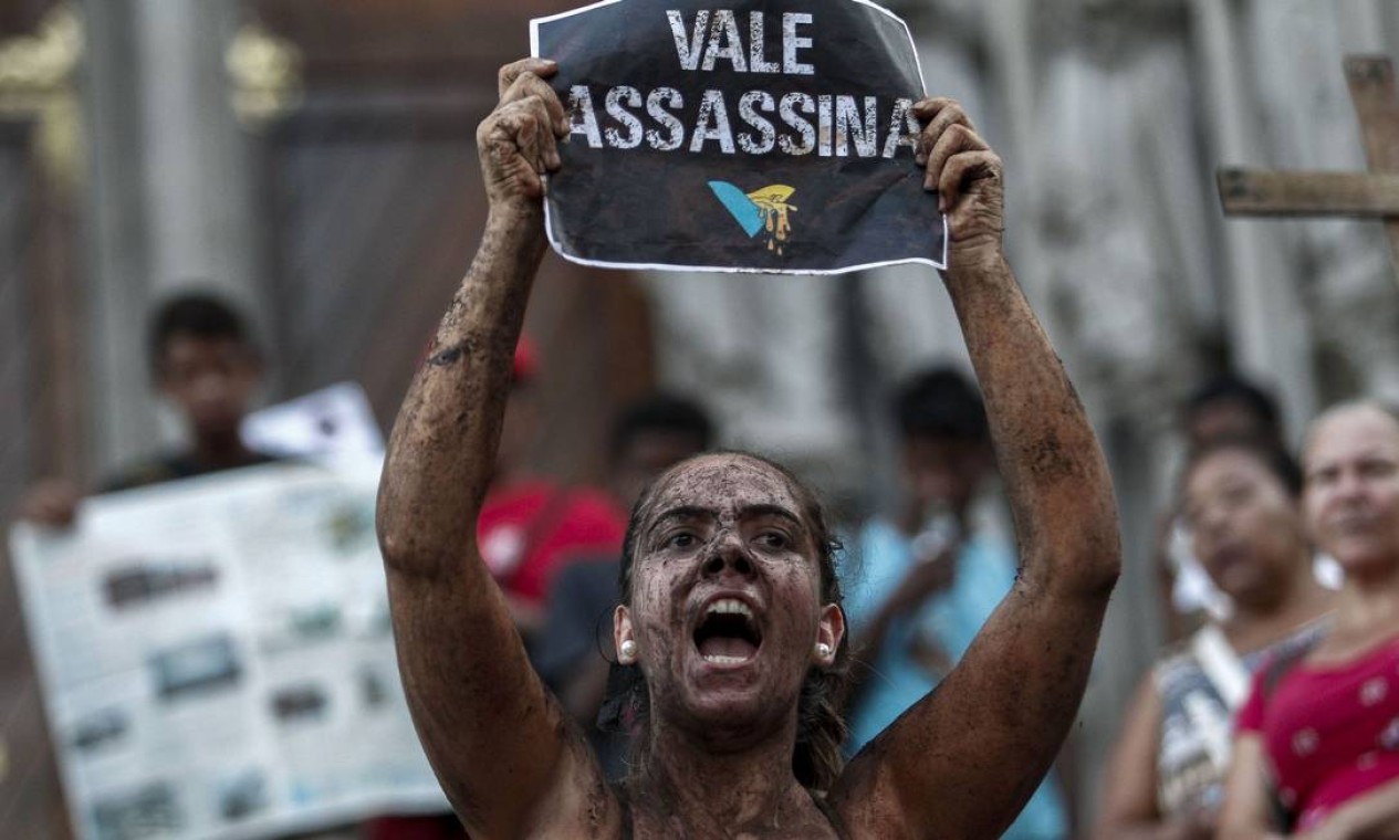 Manifestantes se sujaram de lama para protestar contra a Vale durante um protesto em frente à Catedral da Sé, em São Paulo. Também houve manifestação em frente ao prédio da mineradora no Rio Foto: MIGUEL SCHINCARIOL / AFP