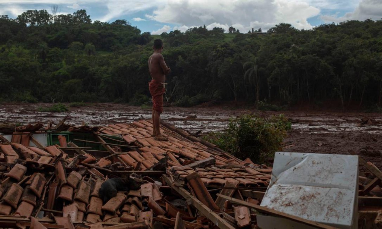 Emerson dos Santos, 30 anos, ficou em pé no telhado da casa de sua família para observar o rastro de destruição deixado pelo tsunami de lama que saiu da barragem da Vale Foto: MAURO PIMENTEL / AFP