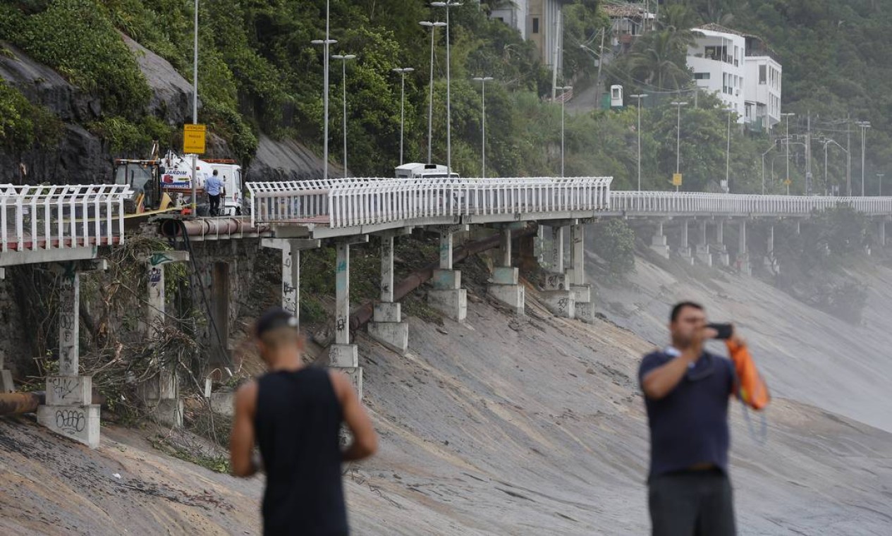 Pedestres fotografam os estragos causados pelo deslizamento de terra na avenida Niemeyer tendo ao fundo parte da ciclovia que despencou Foto: Pablo Jacob / Agência O Globo