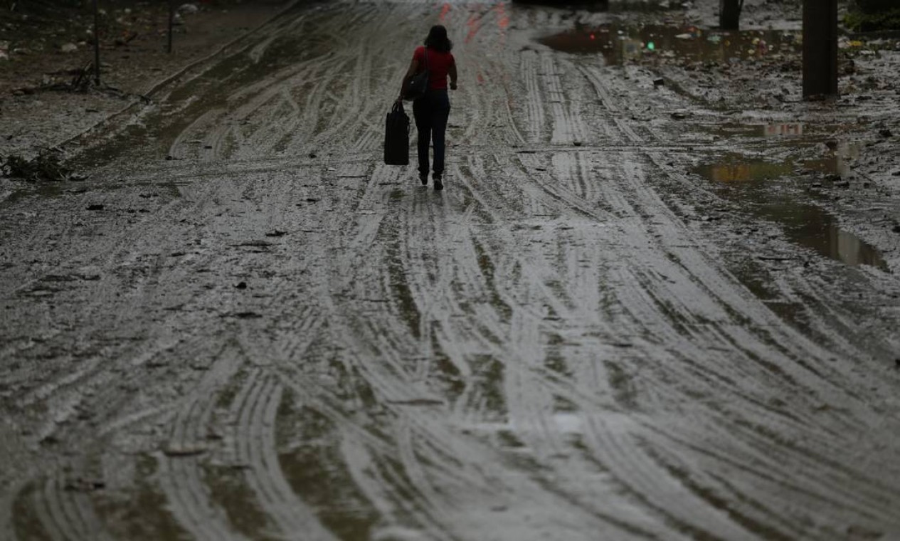 Na manhã desta quinta-feira, uma mulher caminha pela Estrada da Gávea, na altura de São Conrado. A via ficou tomada pela lama devido ao temporal que atingiu a cidade Foto: Gabriel Paiva / Agência O Globo