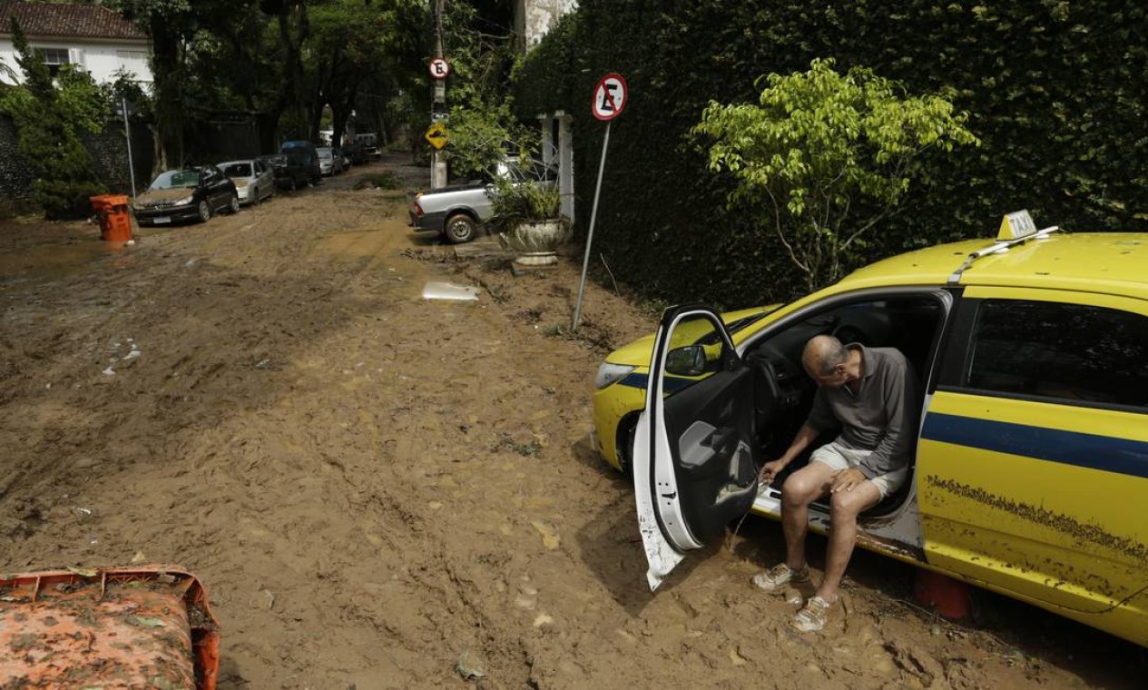 Em São Conrado, na Rua Golf Club, taxista tira a água do carro com um copinho | Foto: Gabriel Paiva / Agência O Globo