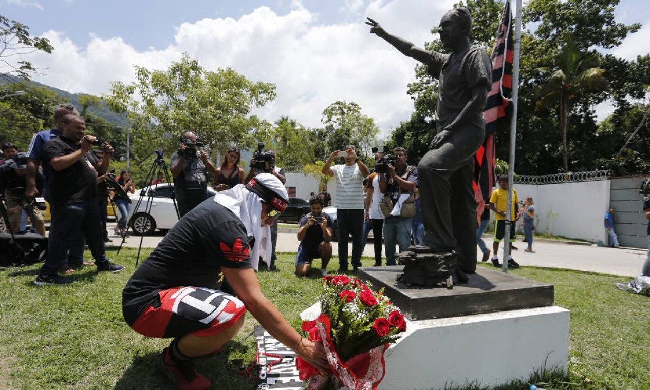 Homem faz homenagem às vítimas do incêndio pondo flores ao pé do monumento de George Helal, que dá nome ao CT do clube Rubro-Negro | Foto: Pablo Jacob / Agência O Globo