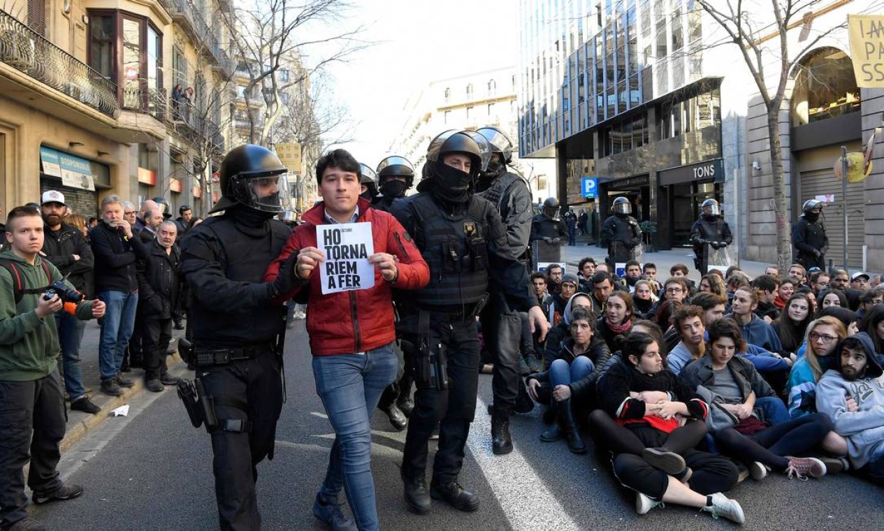 Policiais detêm um homem segurando uma placa com os dizeres "Faríamos de novo", durante o protesto de estudantes em Barcelona Foto: LLUIS GENE / AFP
