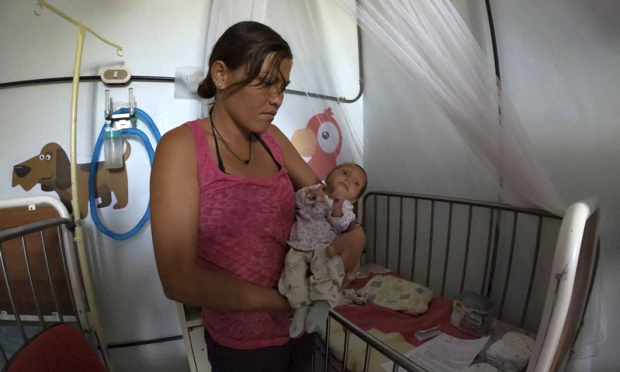 Outra mãe segura seu bebê subnutrido em um hospital em Maracay. Toneladas de medicamentos, alimentos e itens básicos estão estocados em Cúcuta, na Colômbia, à esperar de atravessar a fronteira Foto: YURI CORTEZ / AFP