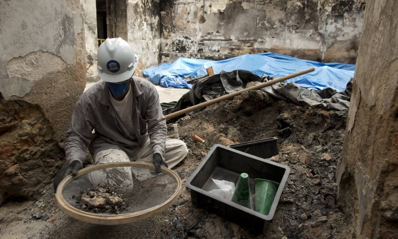 Operário trabalha "peneirando" escombros para tentar encontrar itens do acervo Foto: Márcia Foletto / Agência O Globo