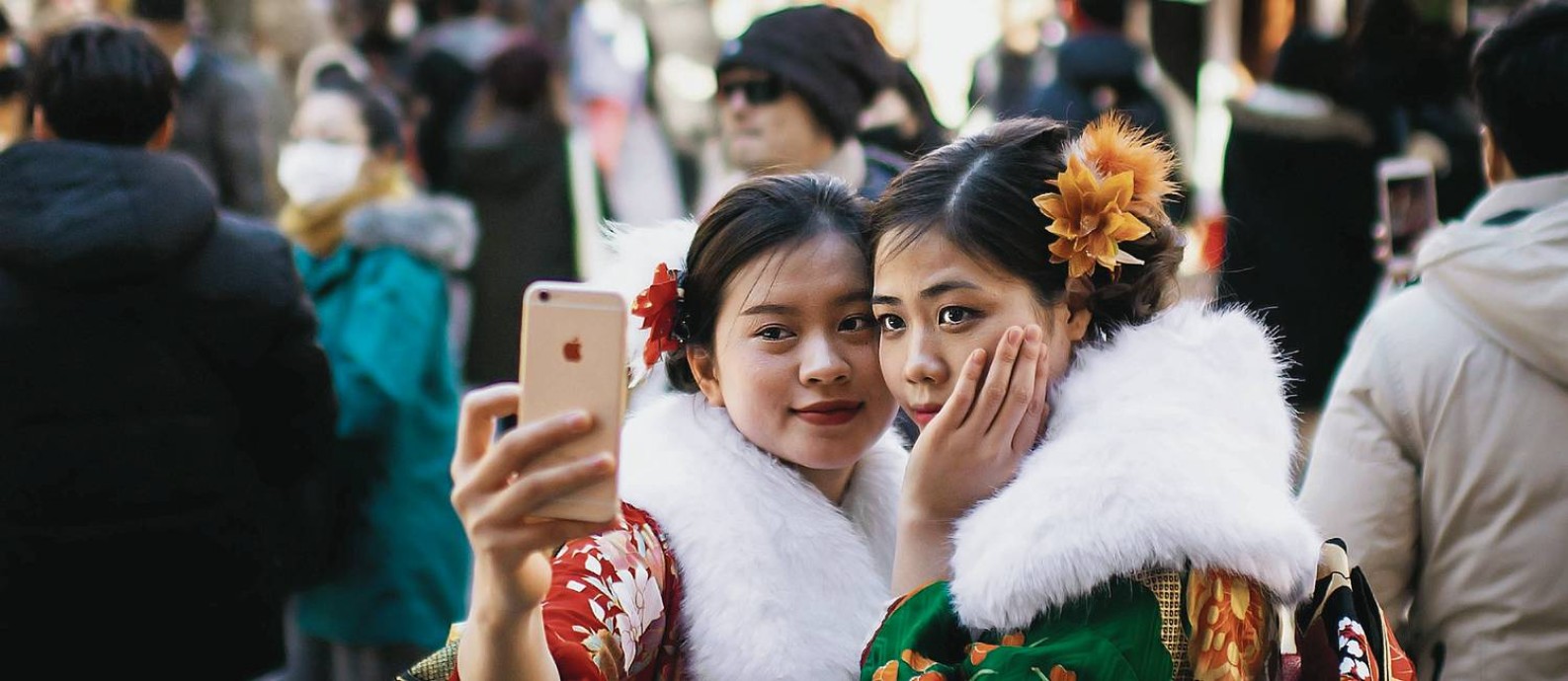 Jovem japonesa segurando o celular contando com a parede de